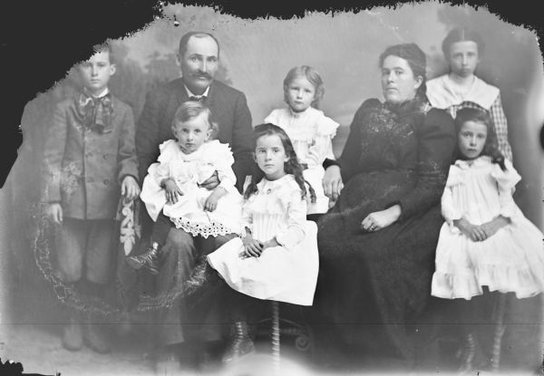 Studio group portrait of a family, including a man, a woman, two boys, and four girls.