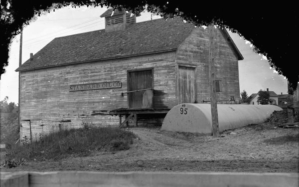View towards the Standard Oil Bulk Station located south of the Black River Falls stockyards. A tank labeled No. 95 is along the side of the building.