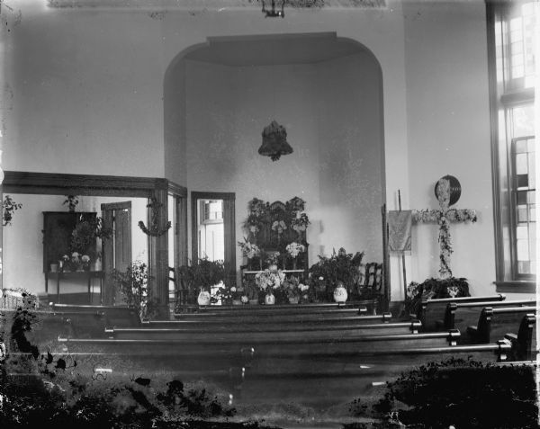 View in the Methodist Church located at Fourth and Harrison. The altar is decorated with flower arrangements. The building burned in 1946.