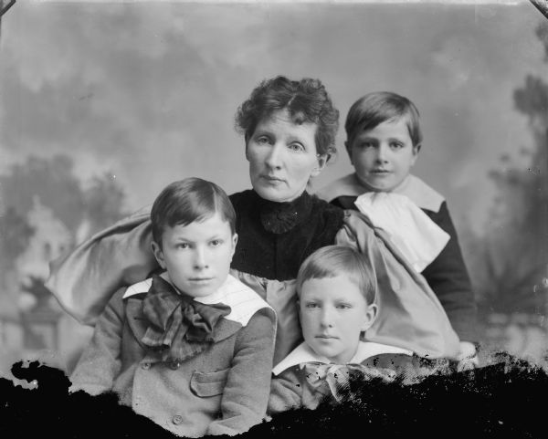 Group portrait in front of a painted backdrop of Mrs. Van Schaick and her sons, Shirley, Harold and Roy.