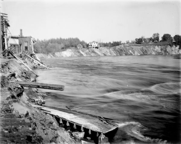 View along shoreline of the Black River after the 1911 flood. The banks are eroded, and power lines are downed.