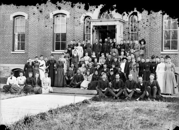 A group portrait of students and faculty from the Teachers' Institute posing in front of the building.