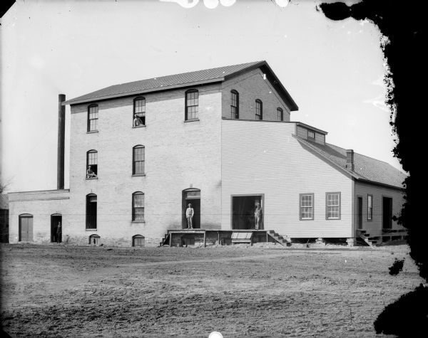 Exterior view of Riverside Mill located on the west side of S. Riverside Road. Men are standing on the loading dock.