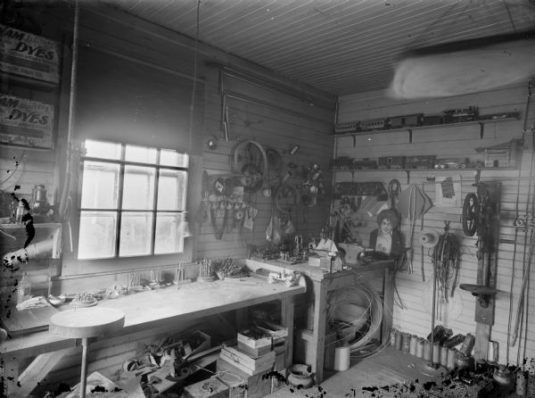 Interior view of a workshop. Model trains are on shelves on the back wall. A model boat is next to an anvil, and a model automobile is on a work table. The envelope is labeled: "Leslie Warner's."