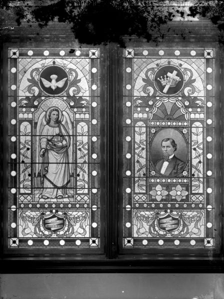 Interior view of a stained-glass window with a dove and angel on the left pane and a crown and cross and a modern-age man on the right pane.
Identified as the Price Window in the Methodist Church located at the northwest corner of Fourth and Harrison Streets.