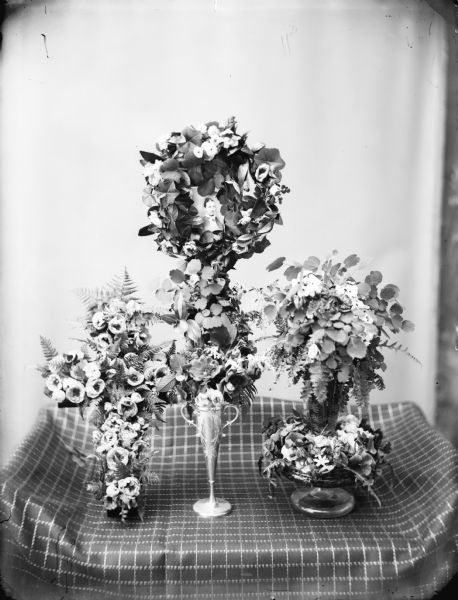 Funeral floral arrangements with a photograph of the deceased placed in the center of one of the tall arrangement in the center.