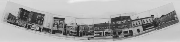 Composite panoramic view of the south side of the 400 block of State Street. Businesses include: Giuseppe's Pizzeria, a record store, Meuer Photoart House, Peet Paint Co., Ethel Woods Corset Shop, Martin's Tailor Shop, Bluteau's Market (meats), Ella's Deli, Catholic Information Center, US Army Recruiting Station, and Gargano's Pizzeria. Several automobiles are parked along the street.