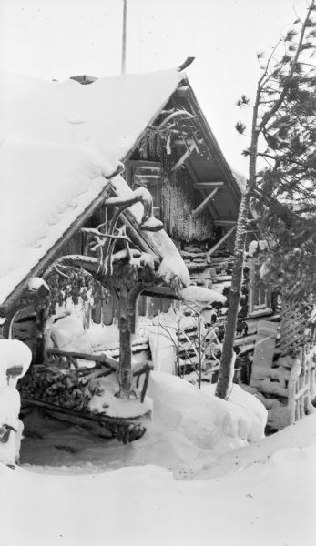 The entrance and gabled front of the main Hotz cottage at Fish Creek, seen after a snowfall. There are rustic branch details under the gables.