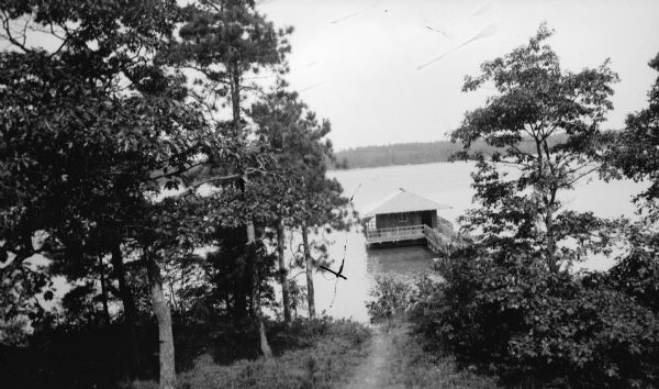 A walkway with rustic railing leads to the Hotz family boathouse on Europe Lake. A well-worn path leads downhill to the water.