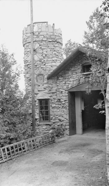 The stone tower and garage at the Hotz compound. There is also a flag pole and rustic fence. A ladder was used to access the lookout atop the tower, with views of Fish Creek Harbor.