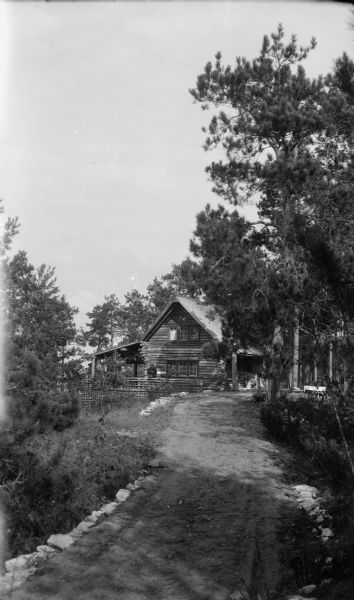 A narrow stone-lined lane leads to the Hotz family cottage on Europe Lake, where two men stand on the porch.  The man on the right is David Kincaid, the caretaker.