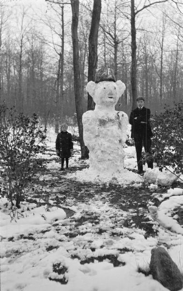 The photographer's son, Ferdinand Leonard Hotz, left, poses with a large snowman and unidentified young man. The snowman wears a basket as a hat.