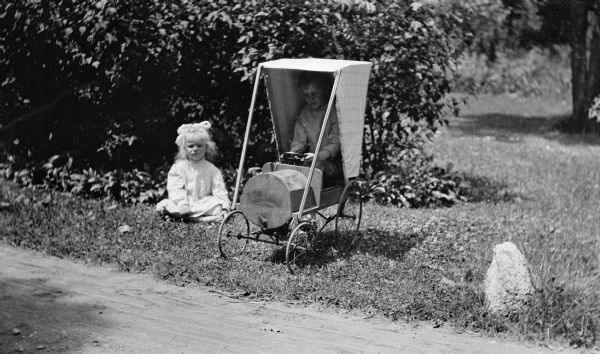 Ferdinand Leonard Hotz sits in a toy car while his sister Margaret (Sissy) sits glumly on the ground.
