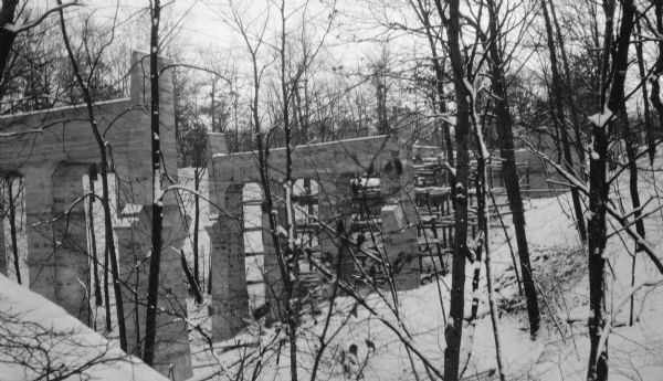 Winter view of new poured concrete bridge supports and scaffolding in a wooded ravine along Sheridan Road.