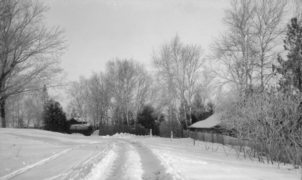 A rustic lattice fence encloses the Hotz family compound on Egg Harbor Road (Highway 42) outside of Fish Creek. There is deep snow on the ground and frost on the trees.