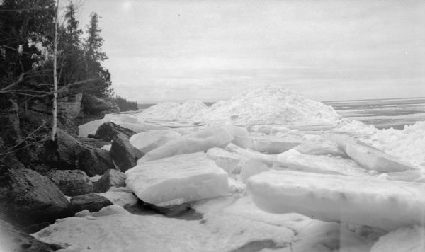 Large slabs and piles of ice line the rocky shoreline of Lake Michigan, possibly at Europe Bay.