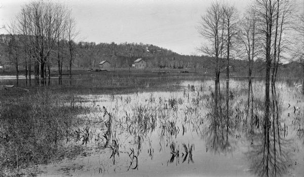 The Thorp house and barn are seen beyond a flooded low-lying area at the rear of the Vorous/Apfelbach farm at Fish Creek. The stone tower and buildings of the Hotz compound are visible on the bluff in the background.