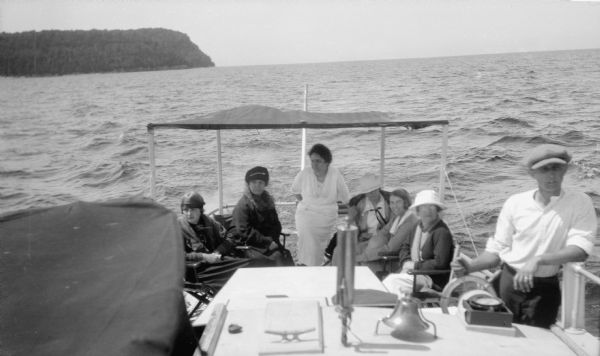 Ferdinand L. (Fedy) Hotz steers the powerboat "Oweene" with 6 women passengers. His mother, Clothilde, sits closest to him.  Door Bluff is in the background.