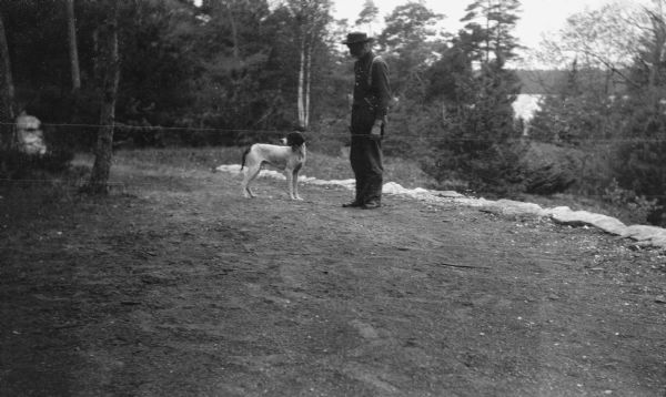 David Kincaid, caretaker of the Hotz Europe Lake estate, poses with a German shorthaired hunting dog. Europe Lake is in the background.