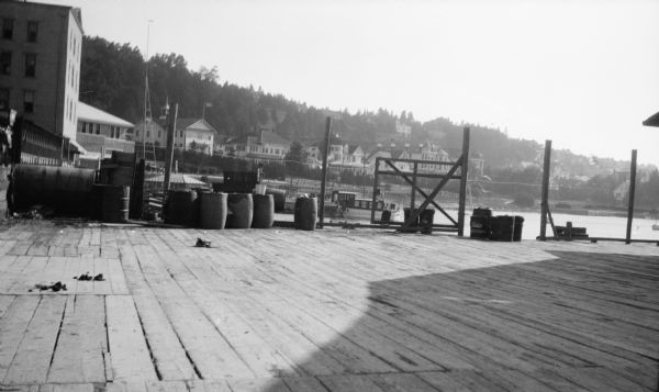 View of Mackinac Island from a wooden pier. There are large houses, some with turrets, facing the water.