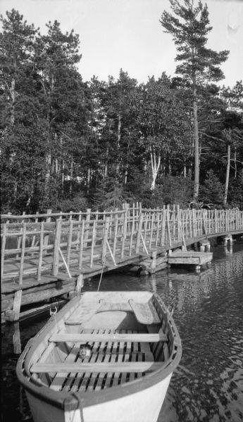 A rowboat is moored alongside the rustic boardwalk to the boathouse at the Hotz family cottage at Europe Lake.