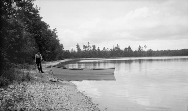 David Kincaid hauls a row boat onto shore with a rope.  Kincaid was the caretaker of the Hotz Europe Lake estate.
