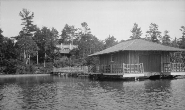 View from the water of the Hotz family cottage, boathouse, and rustic pier on Europe Lake.