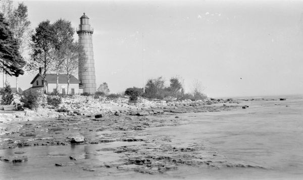 The Cana Island lighthouse and keeper's house with the rocky shore in the foreground.