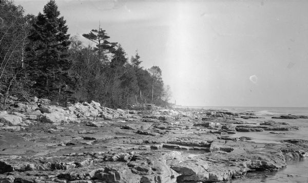 Cana Island lighthouse is seen in the far distance across the stony shoreline along Lake Michigan.