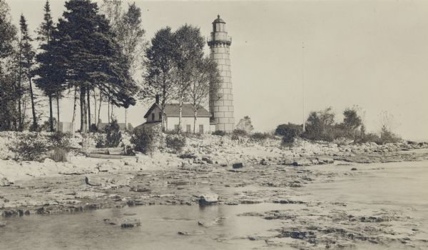 The Cana Island Lighthouse and keeper's house as seen across the rocky shoreline.