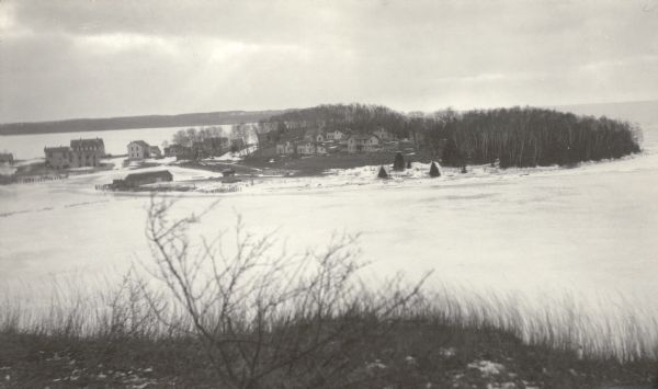 Elevated view of the abandoned town of Fayette. Snail Shell Harbor is in the foreground, with a low warehouse along the boat dock and empty buildings on the far shore.
