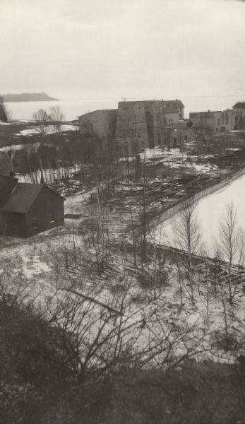 Elevated view of the abandoned Jackson Iron Company furnace complex at Fayette, on the shore of Snail Shell Harbor. Lake Michigan is in the background.