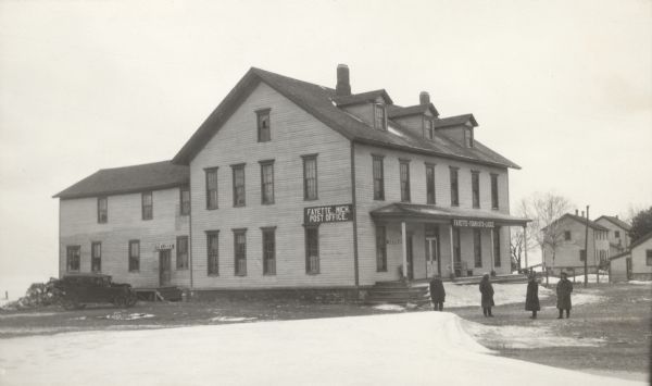 A car is parked alongside the hotel in Fayette. Four men pose near the front porch. As advertised by a large sign, the hotel housed the Fayette Post Office. Other signs identify the building as the Fayette Tourists Lodge and advertise ice cream. Abandoned by the Jackson Iron Company in 1891, Fayette soon became a tourist destination.  The site is now a state park.