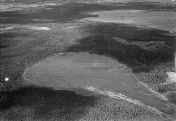 Aerial view, looking northeast, across Mud Lake with North Bay in the background, showing cultivated fields and wooded land.