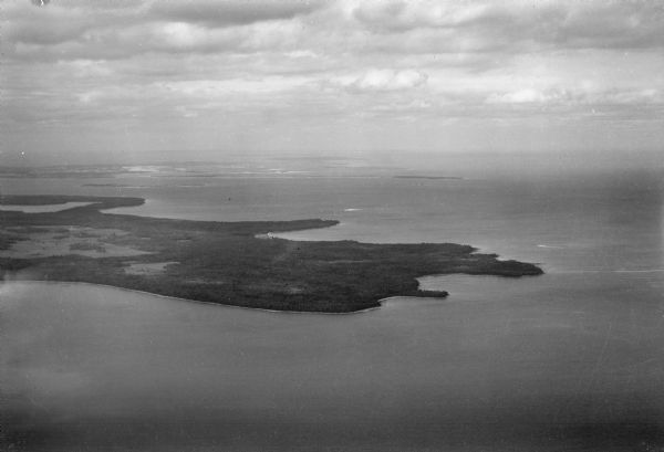 Aerial view looking northeast, with Rowley's Bay in the foreground.  Europe Lake is to the left, with Europe Bay and Newport Bay separated by a narrow peninsula. Plum, Detroit, and Washington Islands are visible in the background. Nearly all the land south (to the right) of Europe lake was owned by Ferdinand Hotz at the time this photograph was taken, and is now Newport State Park.