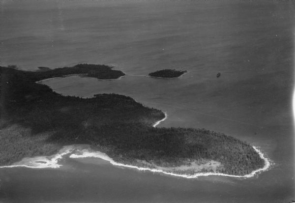 Aerial view from over Moonlight Bay, looking east across Bues Point to Spike Horn Bay and Cana Island. The Cana Island Lighthouse is seen as a ship passes nearby.