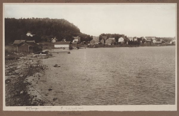 View looking west from the Hotz property on Fish Creek Beach.  The Thorp bathhouse is on the left, with the Welcker bathhouses beyond.  There are houses and commercial buildings in the background; Welcker's Casino is at far right, with it's long roof and central gable.