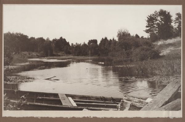 A wooden boat forms the foreground of a view of a stream, probably Shivering Sands Creek, and wetlands, with a sand dune on the right.