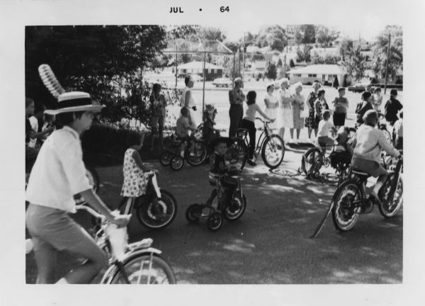 Children on bikes in Madison's Crestwood neighborhood July 4th parade.  In the center is Peter W. Faber (1959-2007) wearing a Mexican cowboy costume, originally worn by his father Robert E. Faber (b. 1933) in 1938.  Immediately behind him is Mary Beth Heasley, a neighbor of the Faber family.