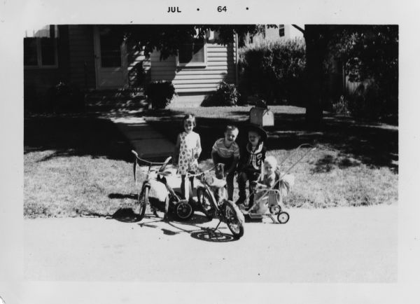 Three children, and a toddler in a stroller, pose at the edge of the street in front of the Faber home at 5706 Dogwood Place, Madison, Wisconsin. A decorated bike and tricycle are parked in front of them.

The children from left to right are Mary Beth Heasley, a neighbor of the Faber family, Michael A. Faber (b. 1957), Peter W. Faber (1959-2007), and William P. (b. 1963) in the stroller.  Peter wears a Mexican cowboy costume, originally worn by his father Robert E. Faber (b. 1933) in 1938.