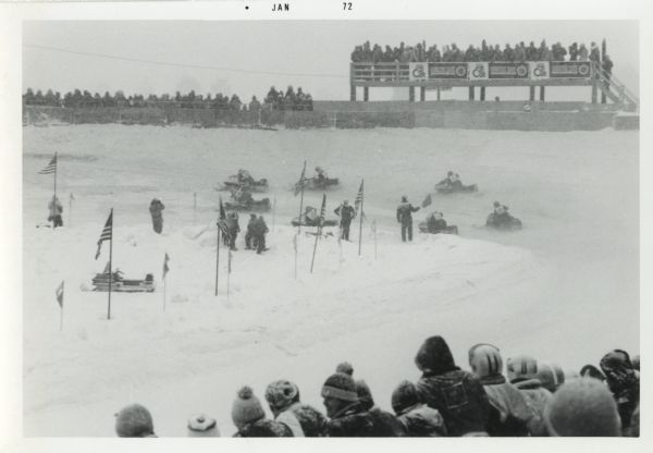 The World Snowmobile Championship showing the track, snowmobiles, competitors, bleachers and spectators.
