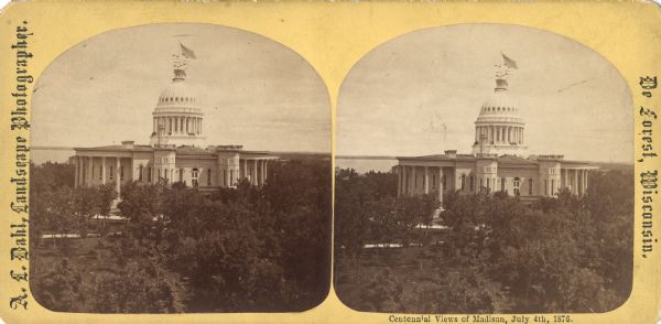 "View of the Capitol, with all the Flags" one of four "Different Views of Parades in the Streets" identified in Dahl's 1877 "Catalogue of Stereoscopic Views." The ceremonies are on the Capitol Square for the Centennial of the United States on July 4, 1876. The elevated view is from the roof of the Park Hotel. Also visible are the Post Office, Mifflin Street, and Lake Mendota in the distance.