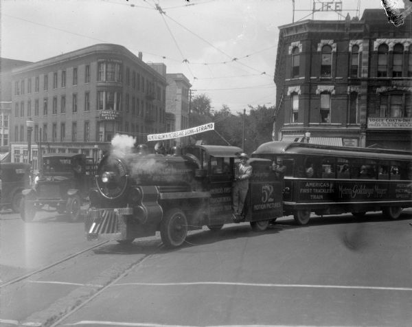 The Metro-Goldwyn-Mayer "Trackless Train" turning onto North Carroll Street from West Mifflin Street. The "Trackless Train" was on a tour from New York to Los Angeles to promote "Good Roads and Good Movies." Also, they promoted the development of a national highway system as advocated by Herbert Hoover, who was, at that time, the 3rd United States Secretary of Commerce.