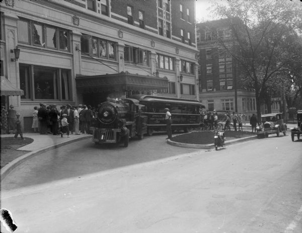The Metro-Goldwyn-Mayer "Trackless Train" parked in front of the Hotel Loraine on West Washington Avenue. The YMCA can be seen on the right. The "Trackless Train" was on a tour from New York to Los Angeles to promote "Good Roads and Good Movies." Also, they promoted the development of a national highway system as advocated by Herbert Hoover, who was, at that time, the 3rd United States Secretary of Commerce.