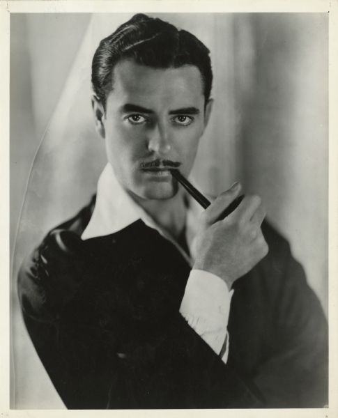 Quarter-length portrait of actor John Gilbert with a pipe in his mouth.