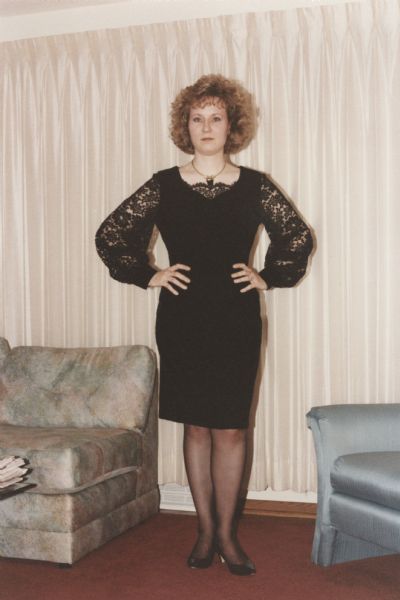 Jill Bremigan in a black velvet and lace cocktail dress that she made from Butterick pattern 6402 (1992). She wore it to a Christmas party held in Madison, Wisconsin, by the company her husband, Cary Bremigan, worked for at the time. Jill's hands are on her hips.