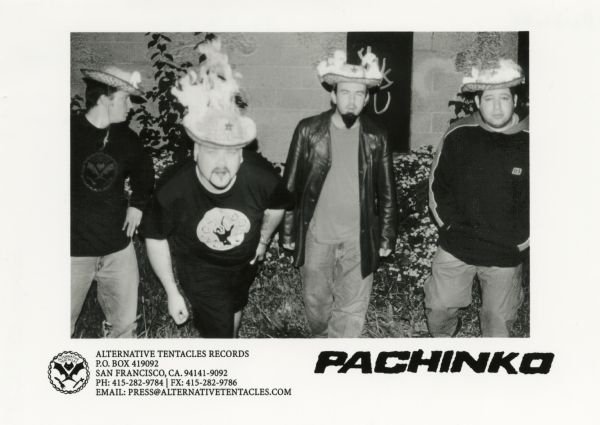 Publicity photograph of the four band members from Pachinko, a Madison, Wisconsin rock band. From left to right are Mike Henry, Brian Bresch, Greg Norman and Josh Gillman. All members appear to be wearing straw hats that are on fire. The band was on the record label Alternative Tentacles Records.