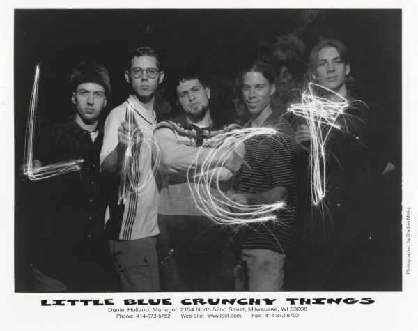 Publicity photograph of Little Blue Crunchy Things, a Milwaukee, Wisconsin rock/hip hop/funk band. Four of the members are writing out the initials "LbCT" in light. From left to right are Bill Backes, Ken Fitzsimmons, Noah Tabakin, Bryan Elliot, and Michael Wengler.
