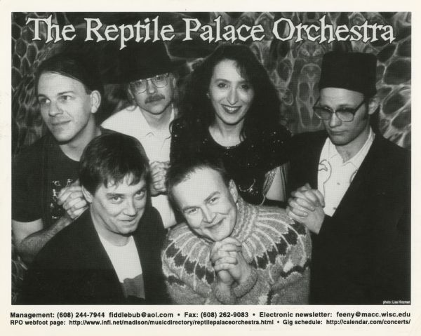 Publicity photograph of the six band members of The Reptile Palace Orchestra, a Madison, Wisconsin band. From left to right in the back row are Seth Blair, Doug Code, Anna Vogel Purnell, and Biff Blumfumgagnge. From left to right in front are Bill Feeny and Siggi Baldursson.