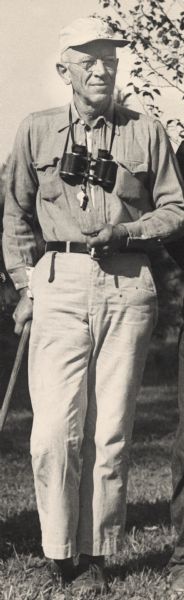 Aldo Leopold, UW Professor of Wildlife Management, posing with binoculars around his neck. He is about to embark on an inspection and bird-watching tour of the Wisconsin River farm, a 140-acre weekend retreat for Leopold.